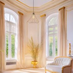 an elegant living room with large windows and gold accents on the walls, along with white couches