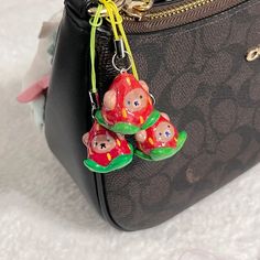 a black purse with three little pigs hanging from it's front pocket, on a white surface