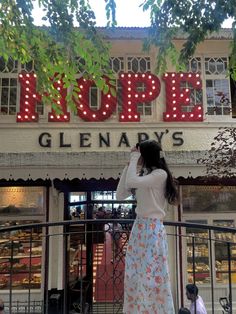 a woman standing in front of a store with the word hope on it's sign