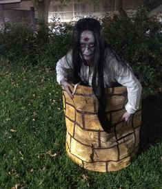 a man dressed up in a costume sitting on top of a brick structure with long black hair