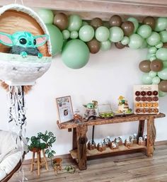 a baby yoda balloon hanging from the ceiling next to a table with balloons and decorations