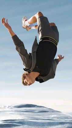 a man flying through the air while riding a skateboard in front of a body of water