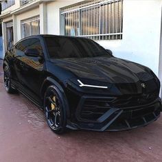 a black sports car parked in front of a white building on the side of a street