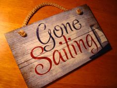 a wooden sign that says gone sailing on it's side hanging from a rope