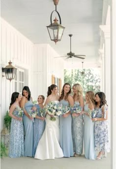 a group of women standing next to each other in front of a white building holding bouquets