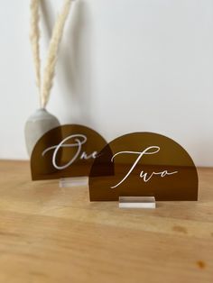 two wooden signs with the word one two written in cursive writing on them