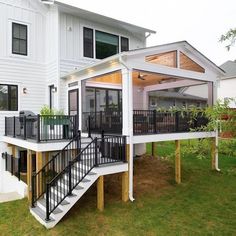 a white house with black balconies and stairs leading to the upper level deck