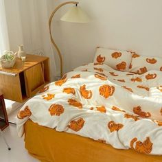 an orange and white bedspread on a bed in a room with a lamp