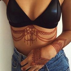 a woman with henna tattoos on her stomach and arm, showing off her bra