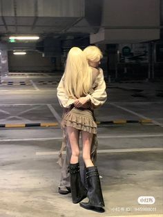 two people standing in an empty parking lot with their arms around each other's shoulders