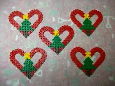 four red and green heart shaped beads on a pink background