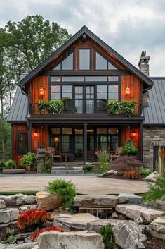 a large house with lots of windows and plants in the front yard, surrounded by rocks