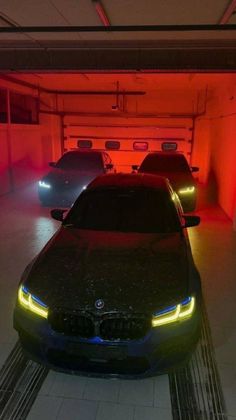 three cars parked in a parking garage with red and blue lights on the side of them