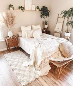 a bedroom with white bedding and plants on the wall above it, along with wooden flooring