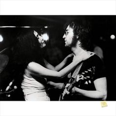 black and white photograph of two people playing guitar together, one man is holding the other's neck