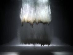 an abstract photo of water pouring from the ceiling in front of a light curtain that appears to be falling down