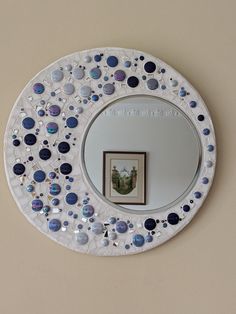 a white circular mirror mounted to the side of a wall next to a framed photograph