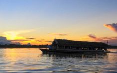 a boat is floating on the water at sunset