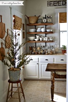 a kitchen filled with lots of white cupboards and wooden shelves next to a window