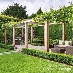 an outdoor living area with green grass and wooden pergoline, surrounded by greenery