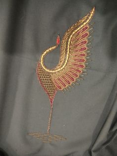 an embroidered bird on a black cloth with gold trimmings and red thread work