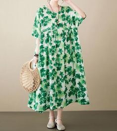 a woman in a green and white dress holding a straw bag