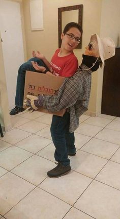 a boy is holding a cardboard box with a puppet on it