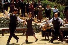 a man and woman dancing in front of a group of people with guitars on the ground