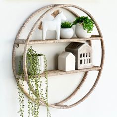 a circular shelf with plants and figurines on it, hanging from the wall