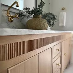 a bathroom vanity with marble counter top and wooden cabinetry, gold faucet