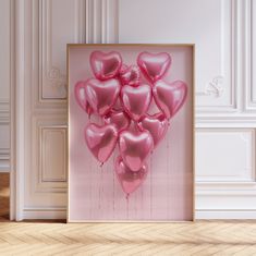 a bunch of pink heart shaped balloons floating in front of a framed photograph on the wall