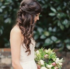 a woman holding a bouquet of flowers in her hand and looking down at the ground