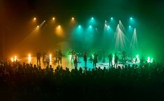 a group of people standing on top of a stage in front of green and yellow lights