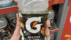 a person holding up a can of g energy drink in front of a store shelf