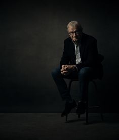 an old man sitting on a chair in the dark