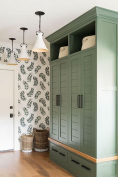 a room with green cupboards and wallpaper on the walls next to a wooden floor