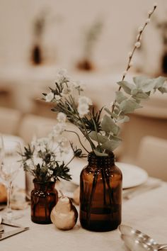 there are two vases with flowers on the table