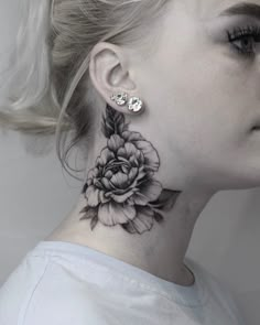 a woman's neck with a black and white flower tattoo on her left side