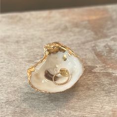 a white and gold shell with two rings on it sitting on a wooden table top