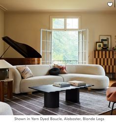 a living room filled with furniture and a grand piano in the window sill,