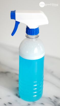 a blue and white plastic bottle with a sprayer on it sitting on a marble surface