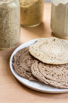 there is a white plate with some bread on it next to two jars filled with different kinds of food