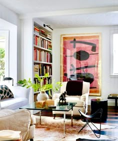 a living room filled with furniture and a painting on the wall behind it's glass table