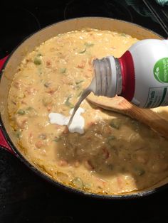 a person pouring milk into a pot filled with food