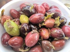 a white bowl filled with red and green olives