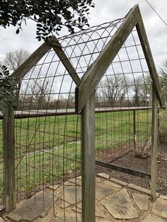 a wooden structure with wire on top in the middle of a grassy area next to a field