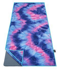 the blue and pink tie dye rug is folded up on top of a gray mat