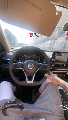 a person sitting in the driver's seat of a car with their hands on the steering wheel