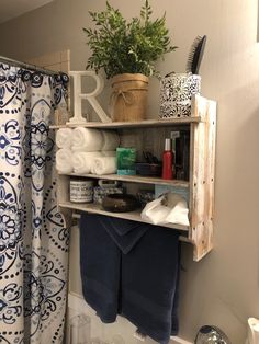 a bathroom shelf with towels, soaps and other items on it in front of a shower curtain