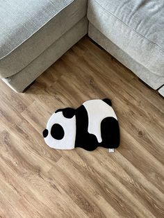 a black and white panda bear rug sitting on the floor next to a gray couch